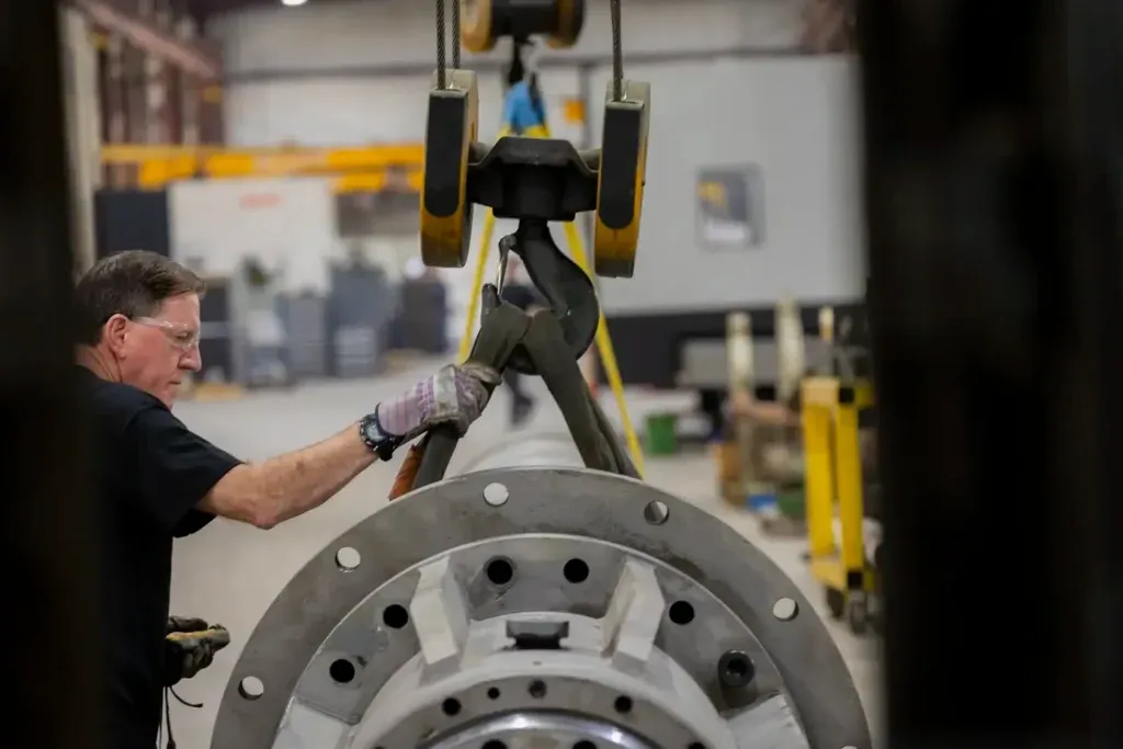 Man securing large cylinder on a hook to lift it